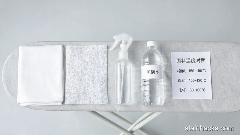 熨衣板旁摆放白色棉质隔热布、网孔隔热布、喷雾瓶与蒸馏水,俯拍静物